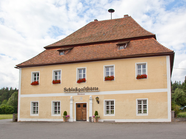 Historisches Gasthaus Schlossgaststätte Melchner mit gelber Fassade, Blumenkästen und Walmdach