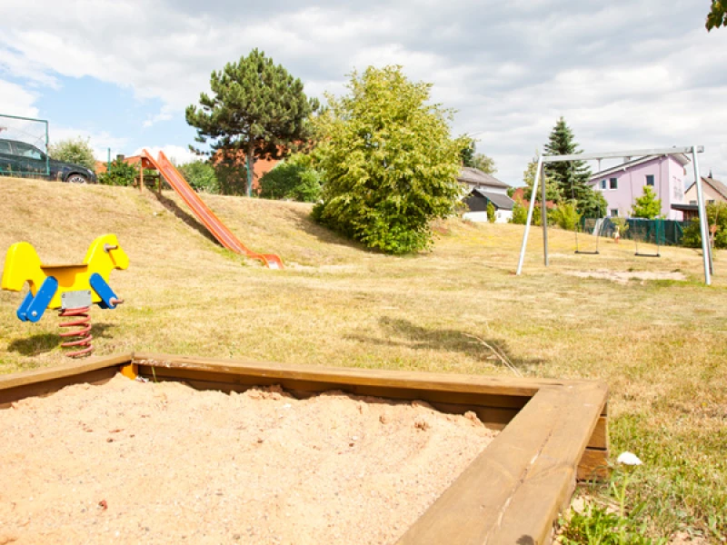 Spielplatz am Hang mit Sandkasten, Federwippe, Hangrutsche und Schaukel