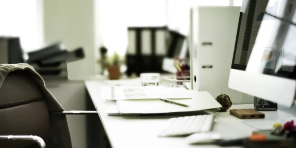 Büroarbeitsplatz mit Monitor, Aktenordnern und Schreibtisch