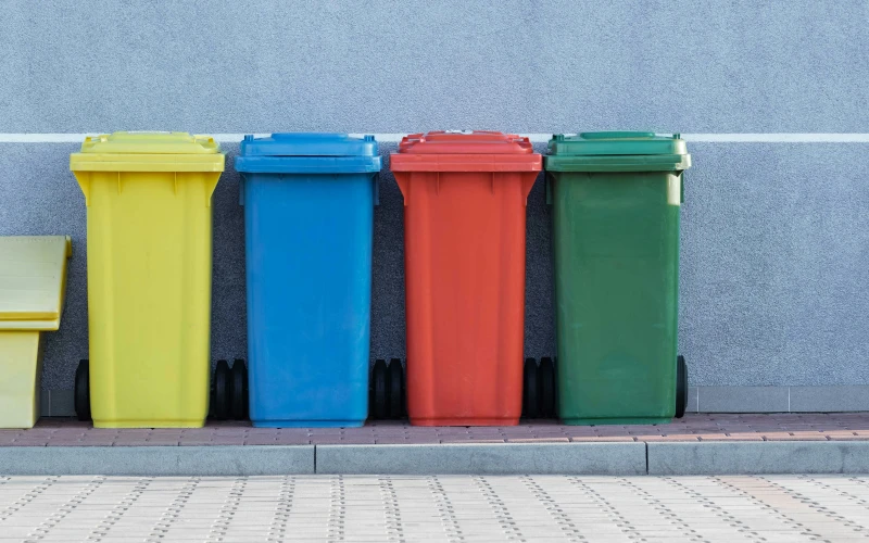 vier Mülltonnen nebeneinander in den Farben gelb, blau, rot und grün